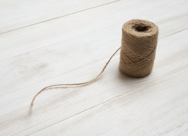 Spool of wool thread on a white wooden background. Top view desktop