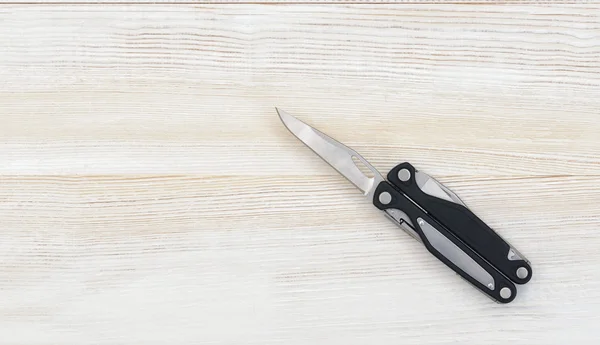 Multi tool with black handles on a white wooden background. Top view of desktop — Zdjęcie stockowe