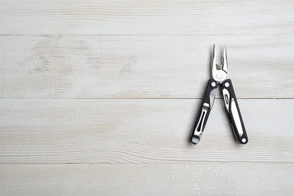 Multi tool with black handles on a white wooden background. Top view of desktop — 스톡 사진