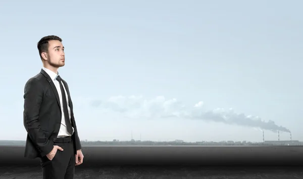 Young man in business suit, standing front of industrial city landscape sunrise. Business, leadership and success concept — Stockfoto