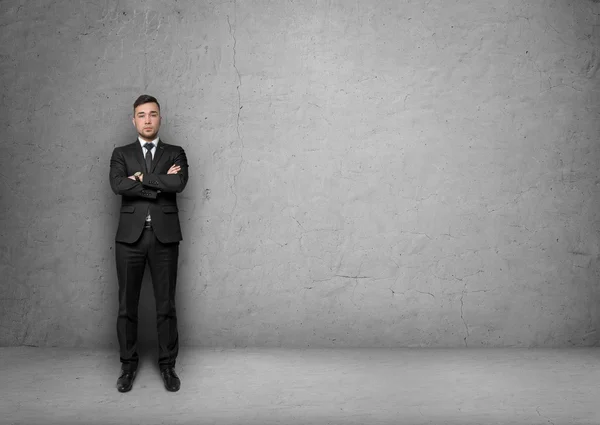 Jeune homme en costume d'affaires, debout devant le fond du mur de béton. Concept d'entreprise — Photo
