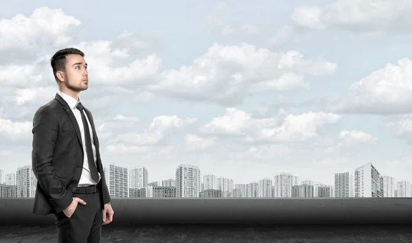 Молодой человек в деловом костюме, стоит перед городским пейзажем на рассвете. Бизнес, лидерство и концепция успеха — стоковое фото