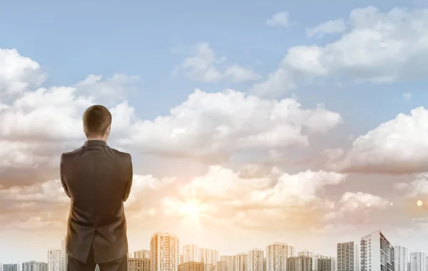 Young man in business suit, standing front of city landscape sunrise. Business, leadership and success concept — Stockfoto