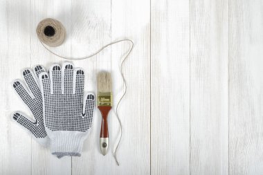 Beyaz ahşap yüzeyde eldiven, fırça ve ipiçeren sanat kompozisyonu.