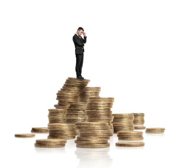 Επιχειρηματίας με μαύρο κοστούμι στέκεται σε σωρό από λαμπερά χρυσά νομίσματα απομονωμένη λευκό φόντο — Φωτογραφία Αρχείου