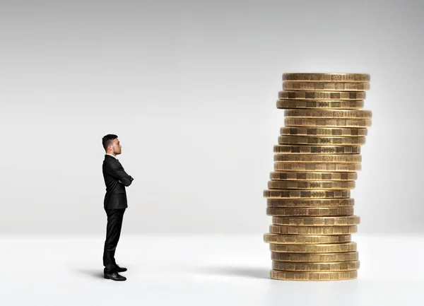 Бизнесмен, стоящий перед стопкой рублевых монет — стоковое фото