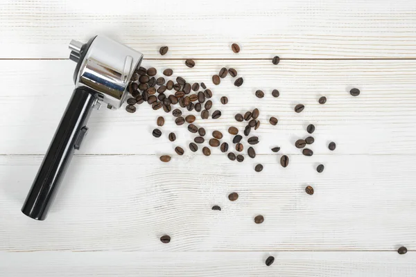 Portafilter lidar com grãos de café espalhados na superfície de madeira na vista superior — Fotografia de Stock