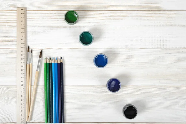 Bovenaanzicht van verf penselen en een centimeter liniaal met kleurrijke gouache containers op houten achtergrond. — Stockfoto