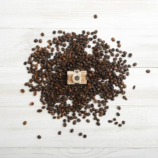 Layout de câmera dourada pequena em um monte de grãos de café — Fotografia de Stock