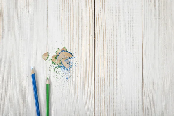 Matite di colore verde e blu con i suoi trucioli su tavola di legno — Foto Stock