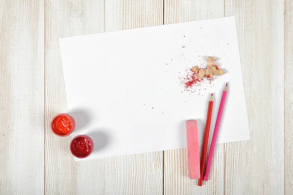 Bovenaanzicht van ontwerper werkplek uitgerust met rood-roze gouache potten, kleurpotloden, krijt, schaafsel en Witboek — Stockfoto