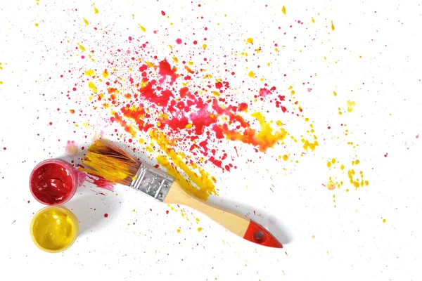 Paint brush with red and yellow gouache sprays near on white canvas in top view — Stock Photo, Image