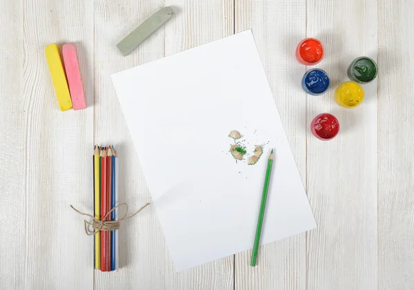Lugar de trabajo del diseñador con lápices de colores, pincel, tarros de gouache, tiza y un papel blanco en la vista superior — Foto de Stock