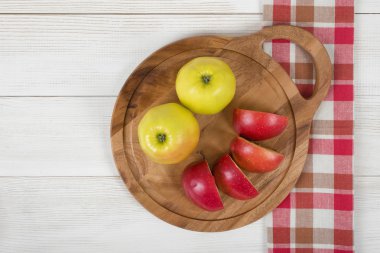 Yellow and red apples laid on a cutting wooden board