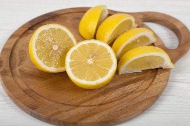 Sarı limon dilimleri ve yarım bir kesme tahtası üzerinde