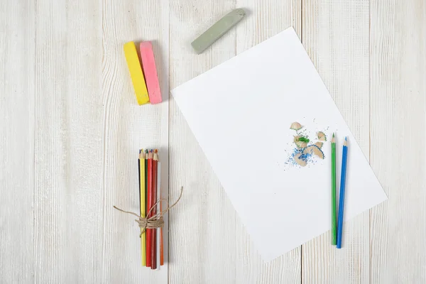 Luogo di lavoro del designer con matite colorate, pennello, barattoli di guazzo, gessetti e una carta bianca in vista dall'alto — Foto Stock