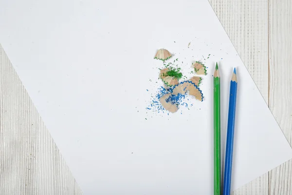 Flat lay of different colored pencils and shavings with white paper — Stock Photo, Image
