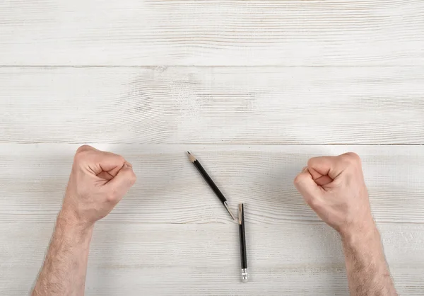 Nahaufnahme maskuline Fäuste geballt auf Holztafel mit gebrochenem Stift — Stockfoto