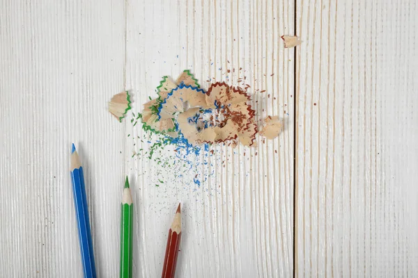 Επίπεδη θέσει διάφορα χρωματιστά μολύβια και ροκανίδια στο τραπέζι — Φωτογραφία Αρχείου