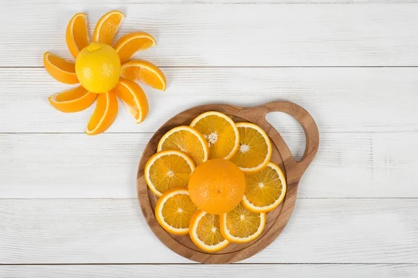 Orange slices are well decorated on cutting board with a lemon.