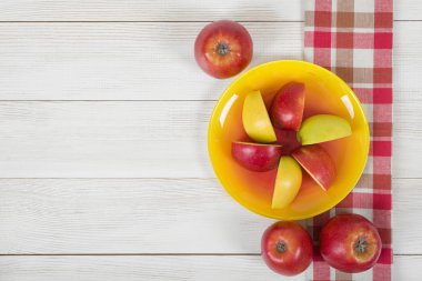 Top görünümünde damalı mutfak masa örtüsü ile ahşap yüzey üzerinde elma..