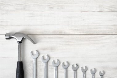 Açık alana sahip ahşap yüzeyde çekiç ve farklı büyüklükteki anahtarlar dahil olmak üzere inşaat araçlarının üst görünümü.