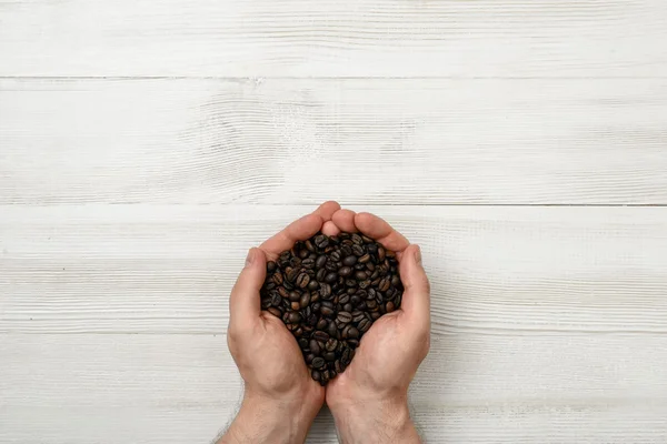 Close-up mãos de homem segurando um punhado de grãos de café — Fotografia de Stock