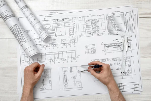 Primo piano mani di uomo in possesso di un divisore di ingegneria su disegno piano in vista dall'alto — Foto Stock