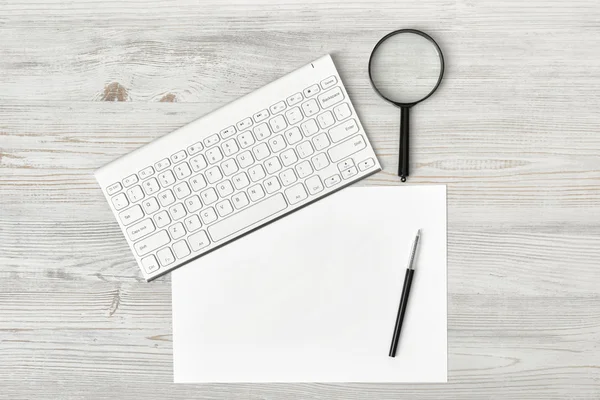 Trabajo de oficina con teclado, bolígrafo, papel blanco y lupa — Foto de Stock