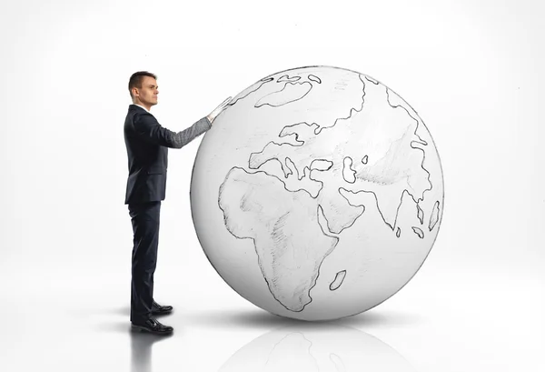 Businessman standing next to a large world globe — Stock Photo, Image