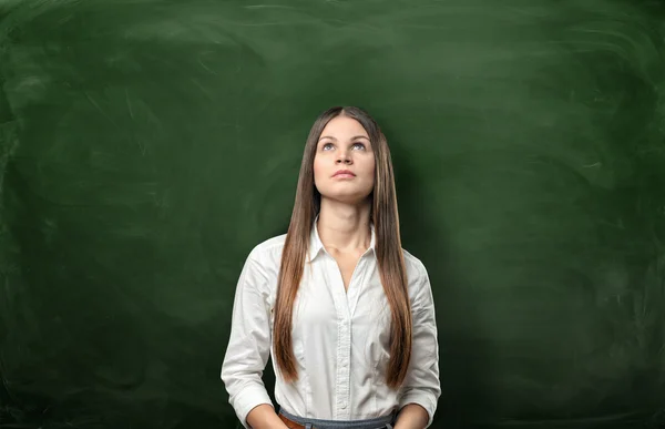 Portret van jonge zakenvrouw zorgvuldig op zoek naar boven op het schoolbord achtergrond bijgesneden — Stockfoto