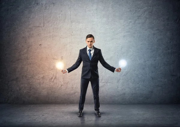 Vista frontal de un hombre de negocios de pie y sosteniendo bombillas brillantes en ambas manos — Foto de Stock