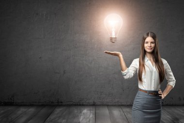 Büyük parlayan ampul tutan genç iş kadını kırpılmış portresi