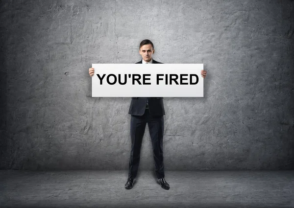 Businessman holding banner with youre fired text on it in his hands — Stock Photo, Image