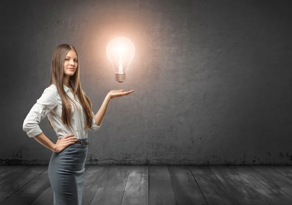 Retrato recortado de uma jovem empresária segurando grande lâmpada brilhante — Fotografia de Stock
