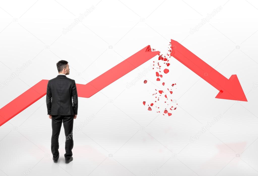 Businessman looking at red broken arrow of falling graph isolated on white background