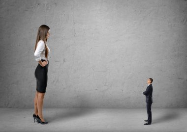 Big young businesswoman standing in front of small businessman clipart
