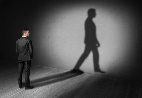 Вид сзади бизнесмена, смотрящего на свою ходячую тень на стене — стоковое фото