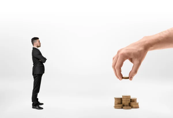 Zakenman kijken naar grote Mans hand maken stapels van gouden munten geïsoleerd op witte achtergrond — Stockfoto