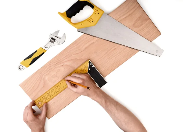 Mans hands measuring wooden plank with iron ruler, on white background — Stock Photo, Image