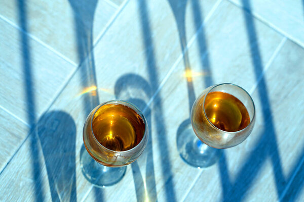 Photo background of wine glasses illuminated by the sun with shadows. Example of glasses with drinks for advertising and design.