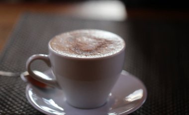 Güneşle aydınlatılmış sütlü güzel bir kahvenin makro fotoğrafı.