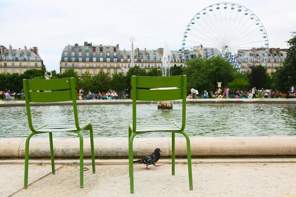 Paříž - 04 července 2016. Tuileries zahrady, zelené židle s výhledem na fontánu a ruské kolo — Stock fotografie
