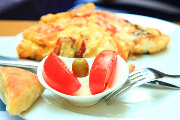 Snídaně: míchaná vejce se zeleninou, rajčata, olivy, chléb — Stock fotografie