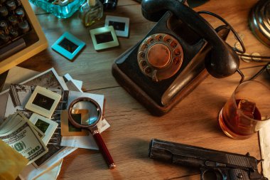 Özel dedektifin masası, siyah renkli telefon, daktilo, lamba, silah ve eski fotoğraflarla dolu bir hayat.