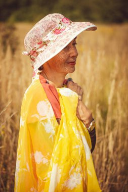 Turuncu elbiseli kadın parkta yürüyor.