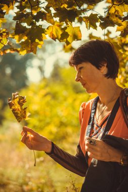 Turuncu elbiseli kadın parkta yürüyor.