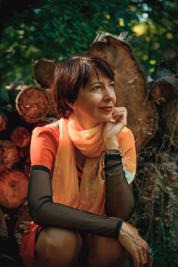 Turuncu elbiseli kadın parkta yürüyor.