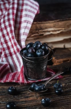 Kırsal ahşap arka planda yaban mersinli küçük bir kova.
