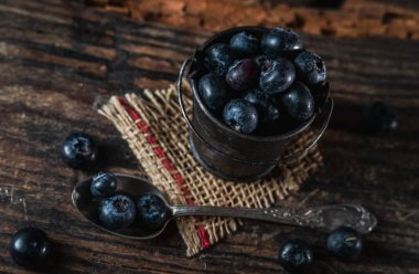 Kırsal ahşap arka planda yaban mersinli küçük bir kova.